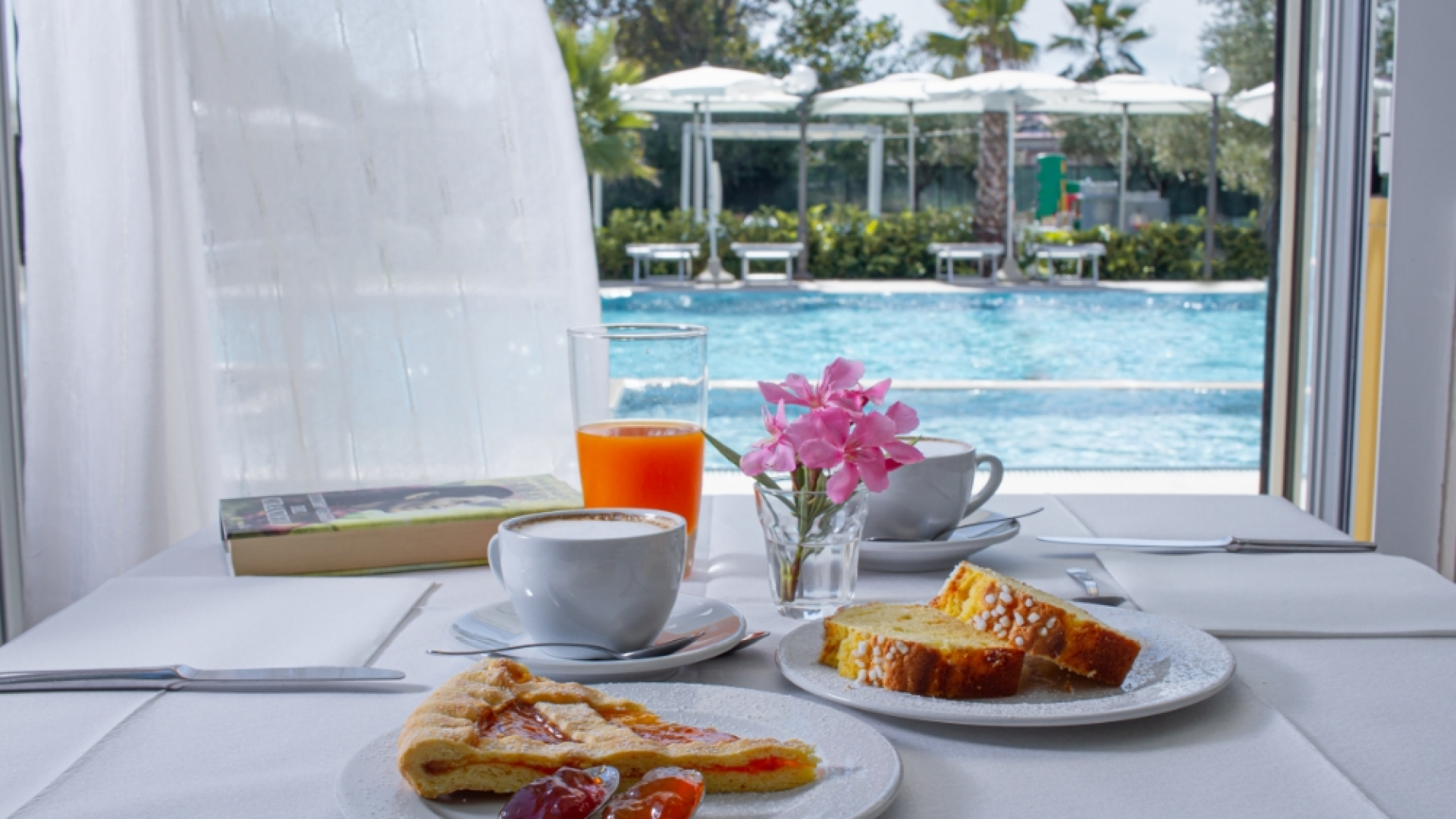 Colazione con dolci, caffè e succo d'arancia, vista piscina.