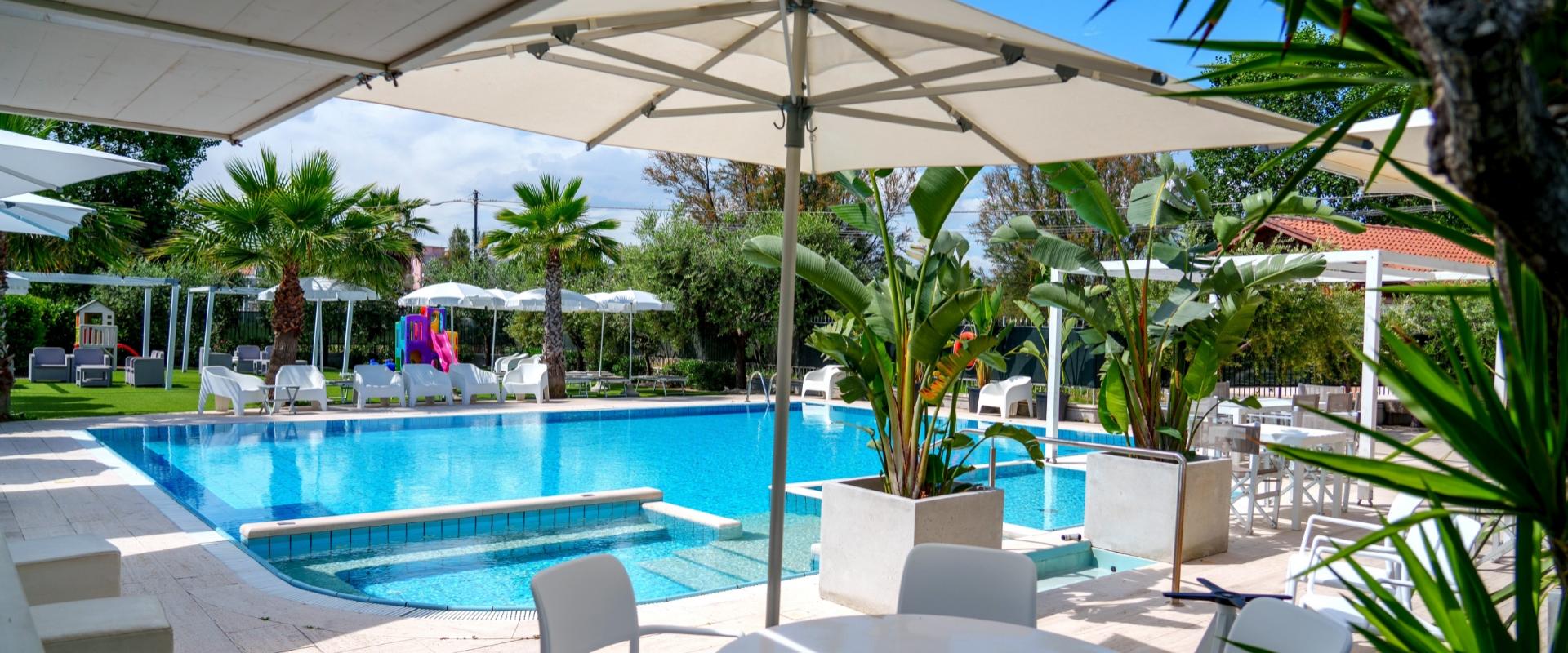 Piscina all'aperto con ombrelloni, lettini e area giochi per bambini.