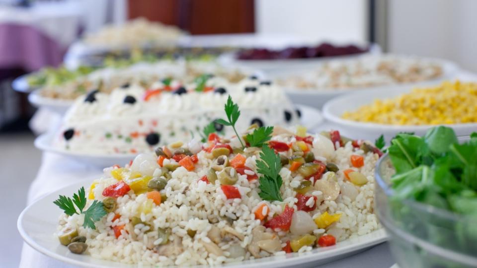 Buffet con insalata di riso, verdure e piatti assortiti.